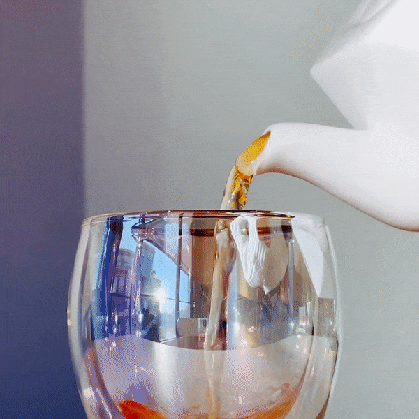 Tea pouring into iridescent glass mug