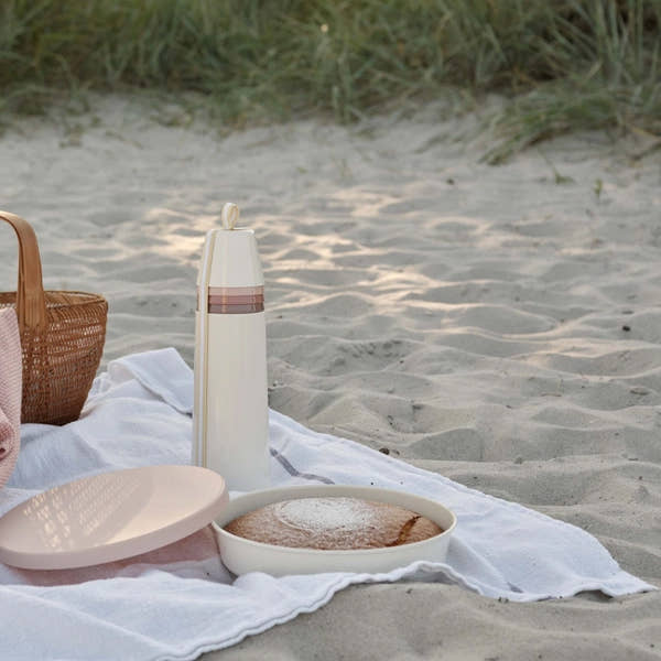 RIG-TIG by Stelton Picnic Vacuum Insulated Bottle with 4 Cups stacked in a beach picnic scene