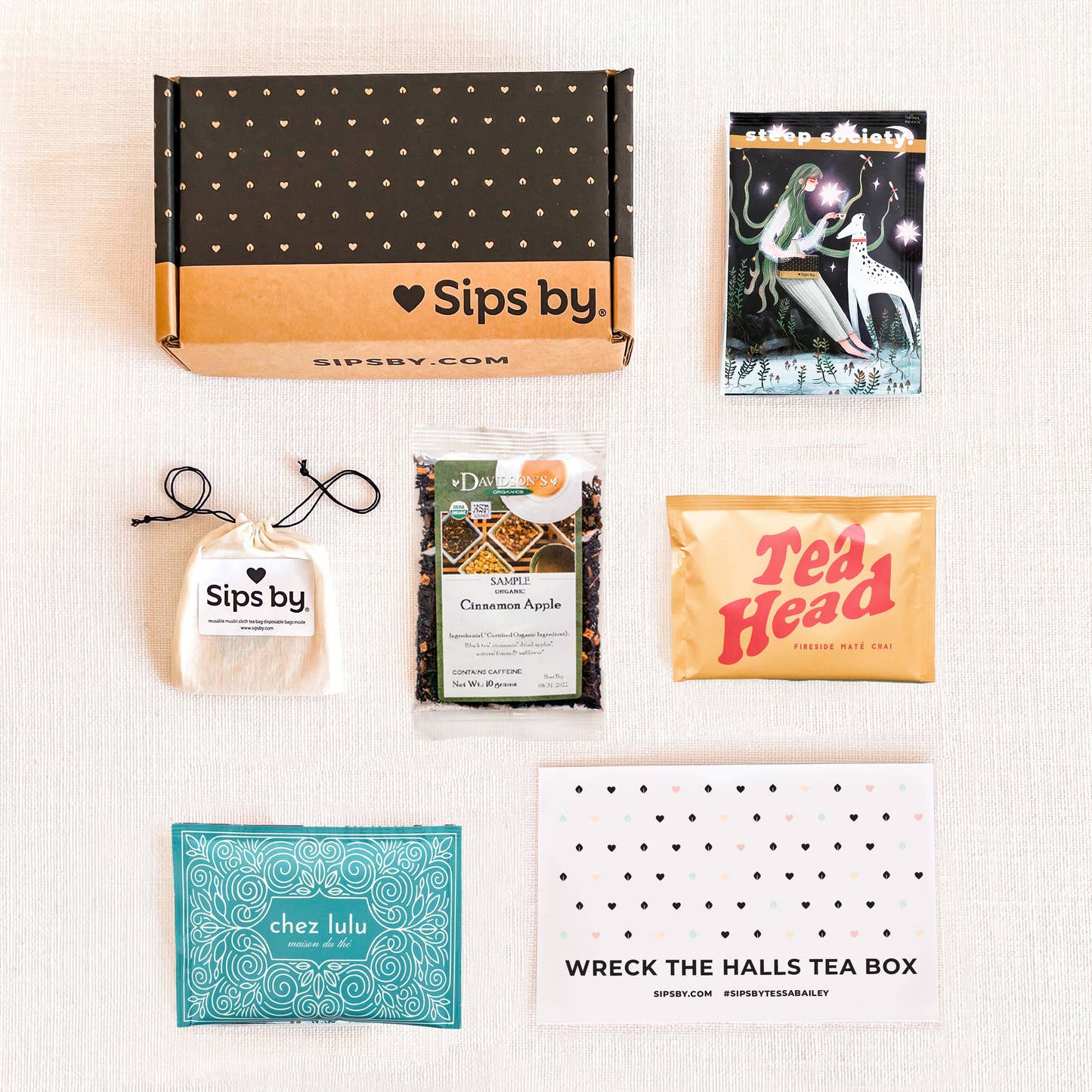 Sips by x Tessa Bailey Wreck the Halls Tea Box contents with four loose leaf tea pouches, a Sips by Box, printed insert, and muslin pouch with tea filters