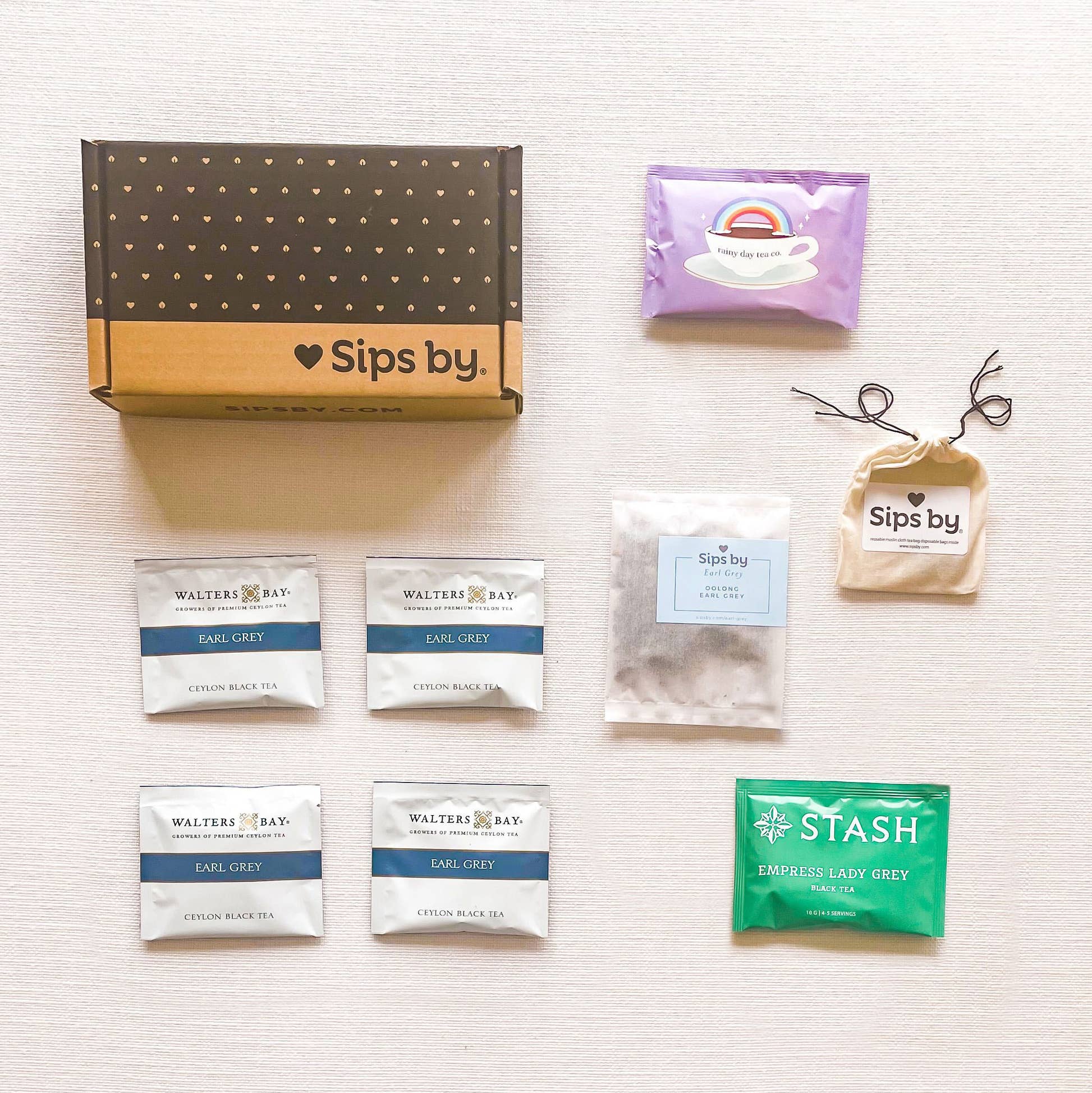 Sips by box with four different earl grey tea samples from Walters Bay, Stash Tea, Sips by Earl Grey, and Rainy Day Tea Co with pouch of biodegradable tea filters