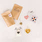 I Love You More Tea Kit with two loose leaf tea pouches, a gold heart infuser, physical Sips by Box gift card, and glass heart mug with brewed tea