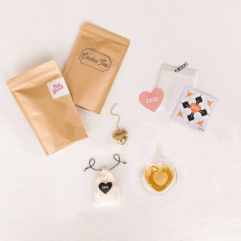 I Love You More Tea Kit with two loose leaf tea pouches, a gold heart infuser, physical Sips by Box gift card, and glass heart mug with brewed tea