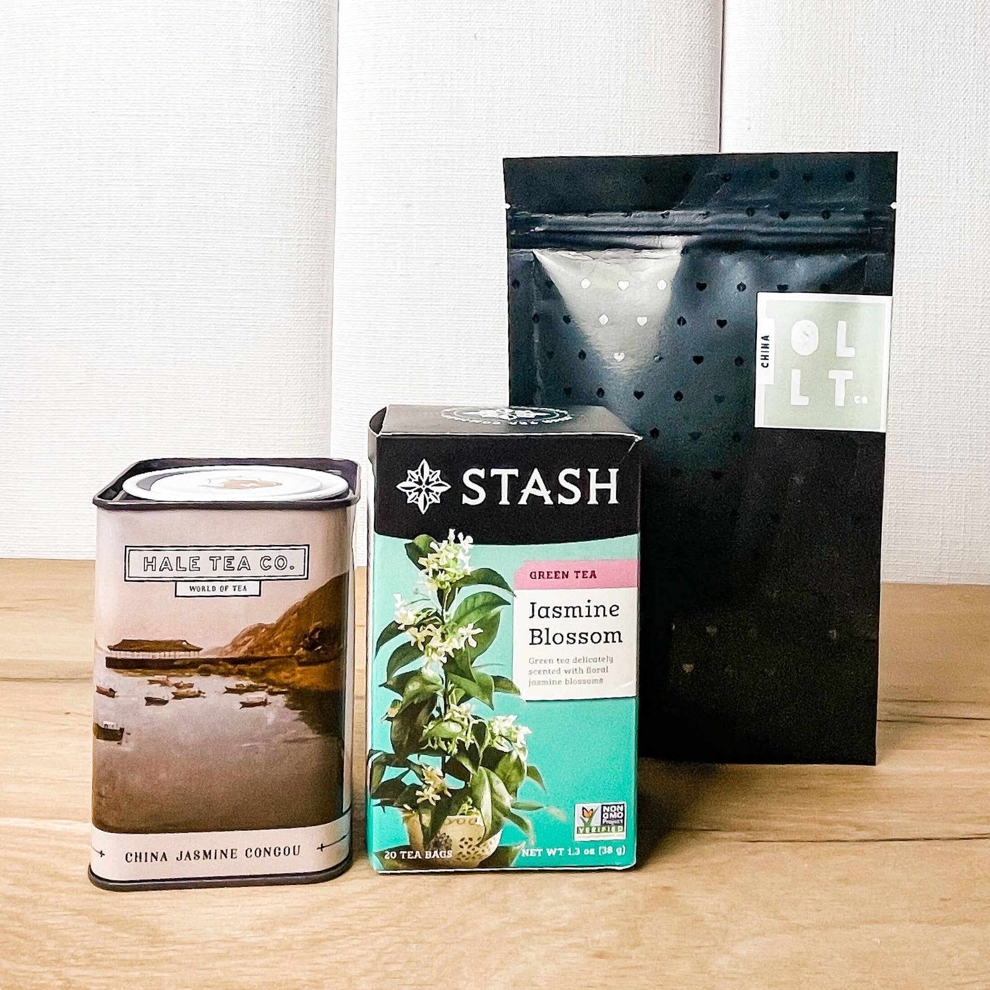 Three full-sized jasmine tea packages including Hale Tea Co tea tin, Stash Tea bags box, and OLLTco jasmine green tea pouch